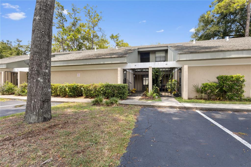 A single-story residential building with a parking lot and gated entryways in front — 7200 SW 8TH AVENUE UNIT H48, GAINESVILLE, FL