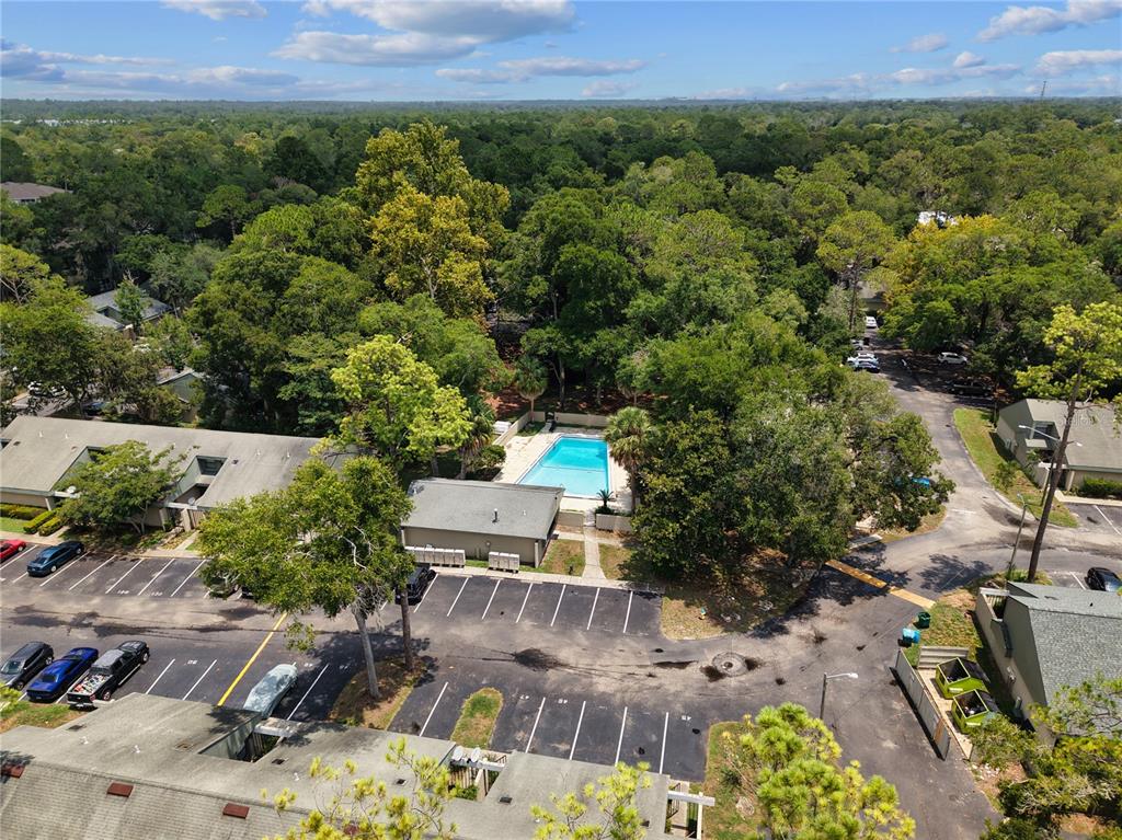 An aerial view shows a community swimming pool surrounded by trees, parking lots, and buildings — 7200 SW 8TH AVENUE UNIT H48, GAINESVILLE, FL