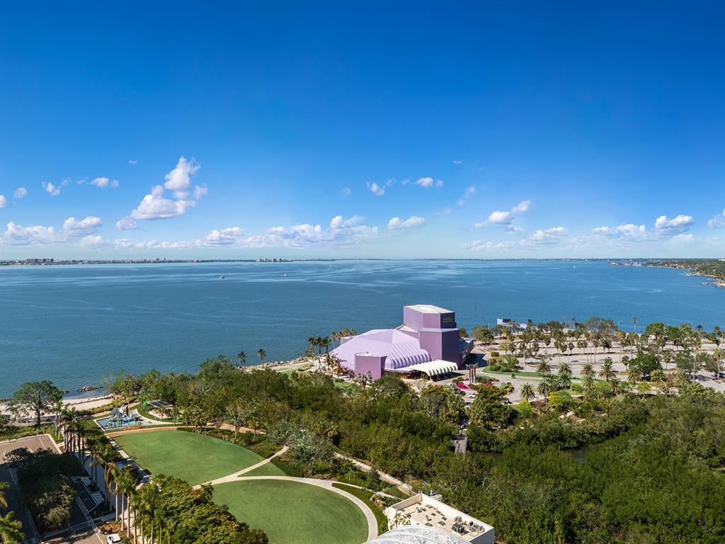 An aerial view shows a purple building near a large body of water and park — 1000 BOULEVARD OF THE ARTS UNIT 1701, SARASOTA, FL