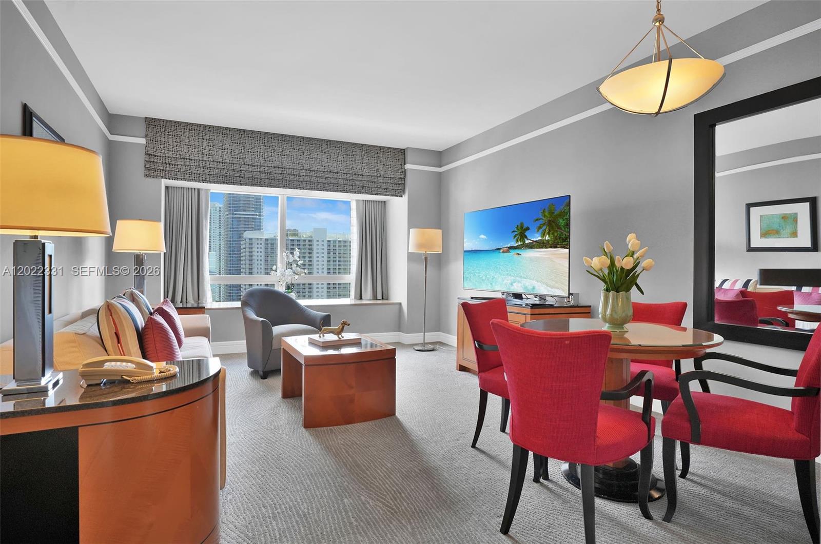 A living and dining area features a sofa, red chairs, and a city view window — 1435 Brickell Ave # 3210, Miami FL 33131, MIAMI, FL