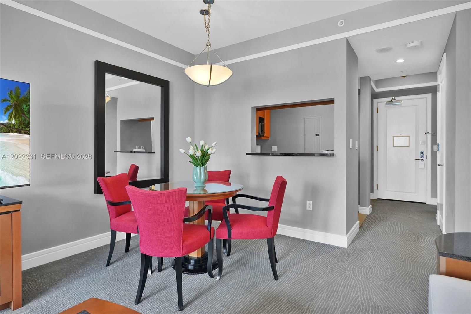 A dining area features a round glass table with four red chairs and a mirror — 1435 Brickell Ave # 3210, Miami FL 33131, MIAMI, FL