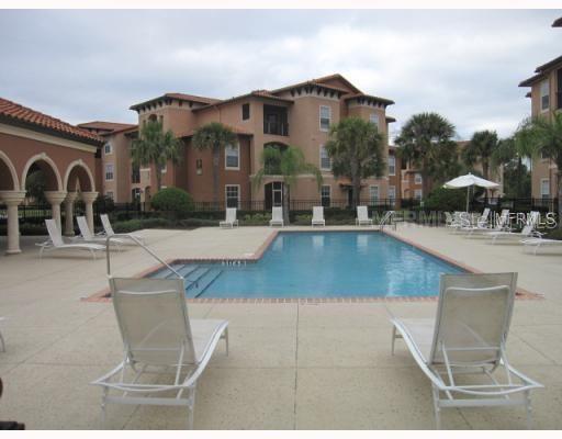 A swimming pool is surrounded by lounge chairs in front of a multi-story apartment building — 6141 METROWEST BOULEVARD UNIT 308, ORLANDO, FL