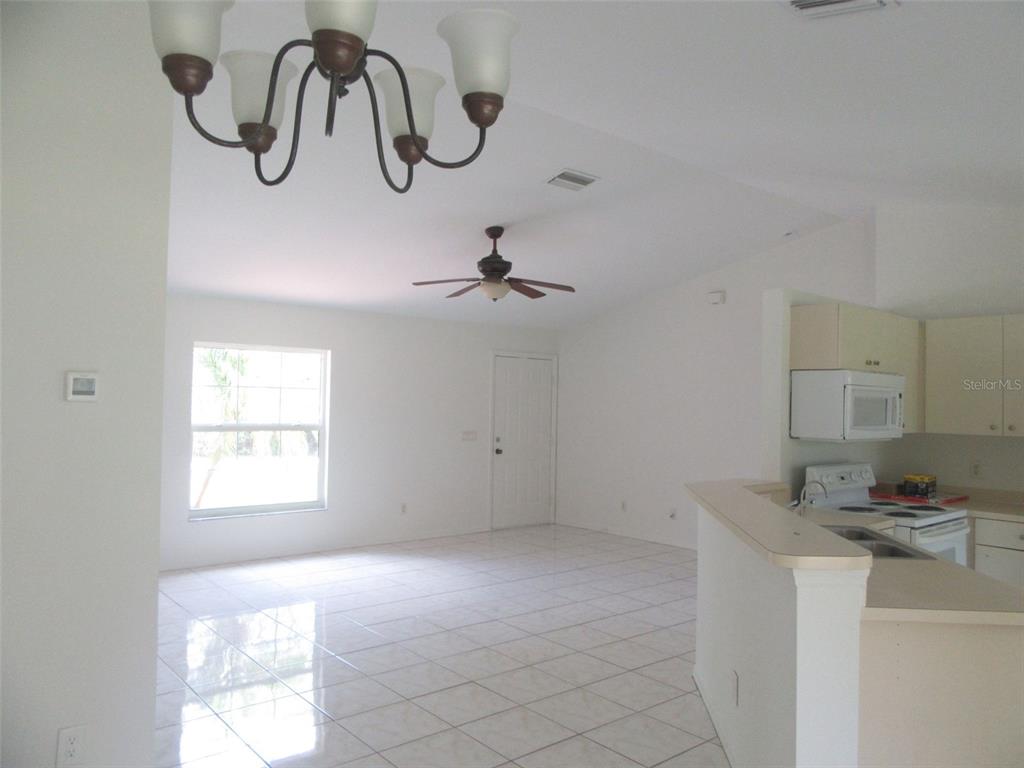 An open-concept living area with tile floors, a ceiling fan, and an adjacent kitchen — 2716 VOGLER LANE, NORTH PORT, FL