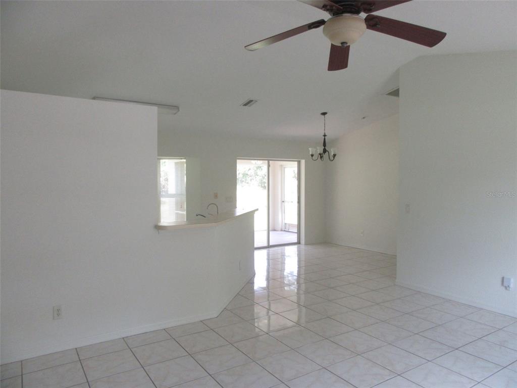 A bright, open-concept living and dining area features white tile flooring and a ceiling fan — 2716 VOGLER LANE, NORTH PORT, FL