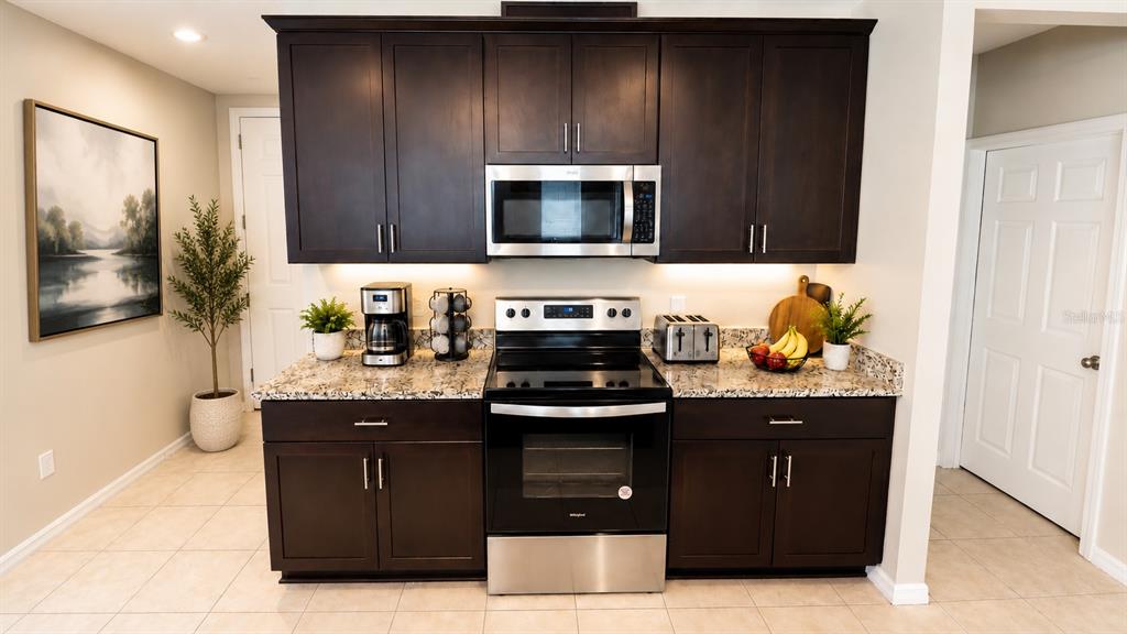 A kitchen features dark wood cabinets, stainless steel appliances, and granite countertops — 2463 SWEET VIBURNUM WAY, OCOEE, FL