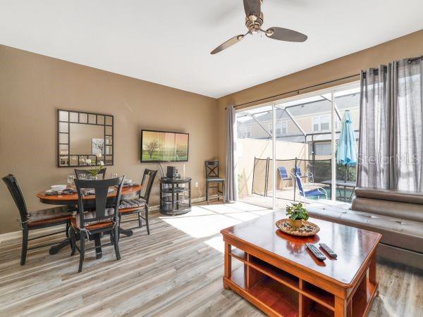 A living and dining area features wood-look flooring, a ceiling fan, and sliding glass doors — 7663 SIR KAUFMANN COURT, KISSIMMEE, FL