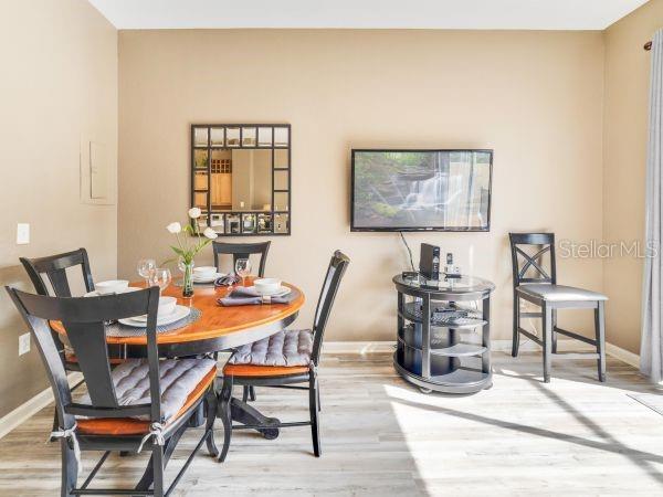 A dining area features a round wooden table with chairs, a wall-mounted television, and mirror — 7663 SIR KAUFMANN COURT, KISSIMMEE, FL