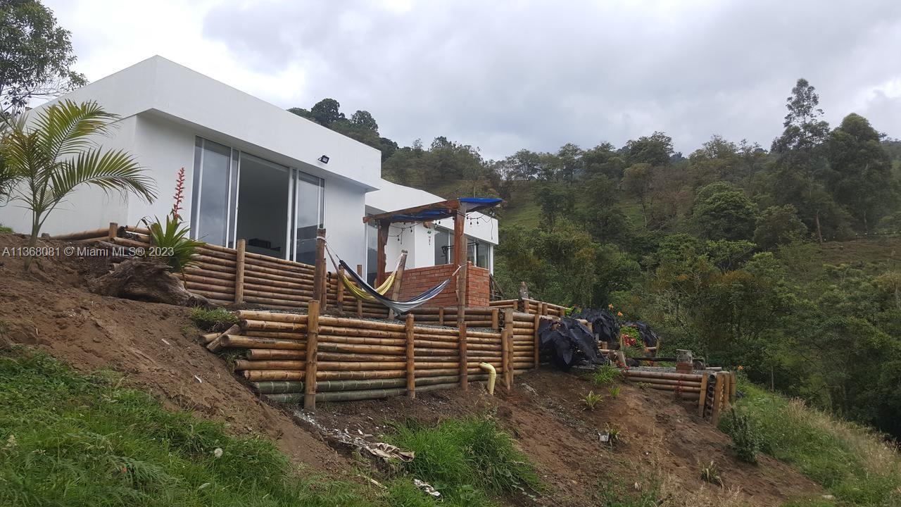 A modern white house features a bamboo retaining wall and a hammock on a hillside — Kilometro 4 Via Salento, Toche, Quindio, SA, SA