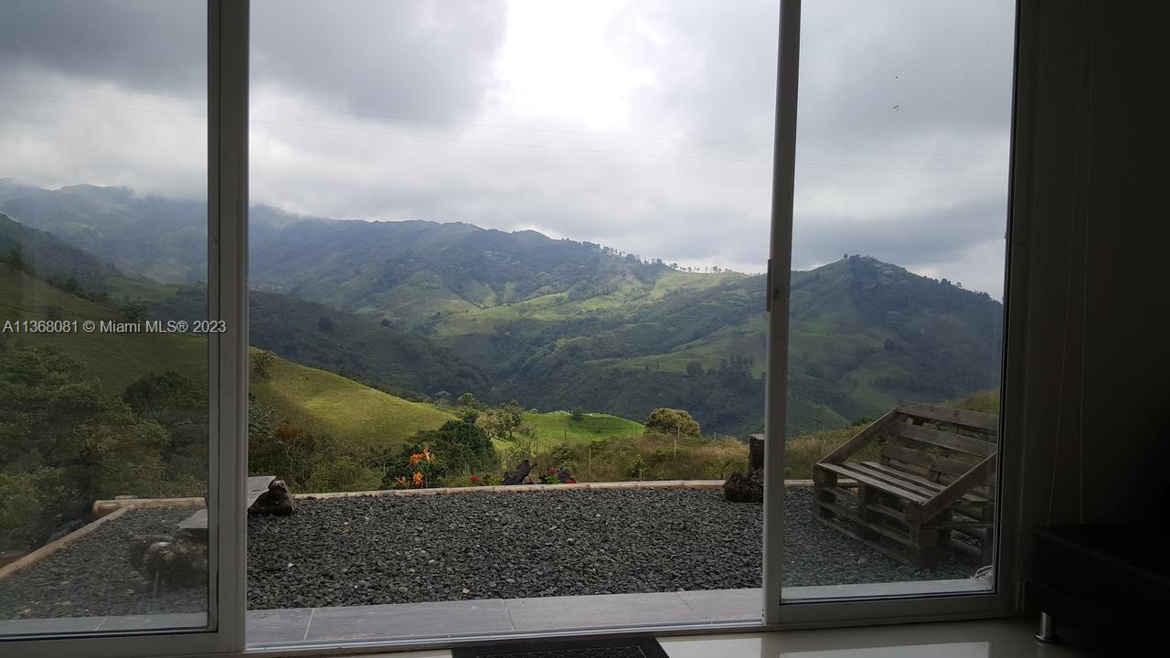 A view of rolling green mountains through a large sliding glass door — Kilometro 4 Via Salento, Toche, Quindio, SA, SA