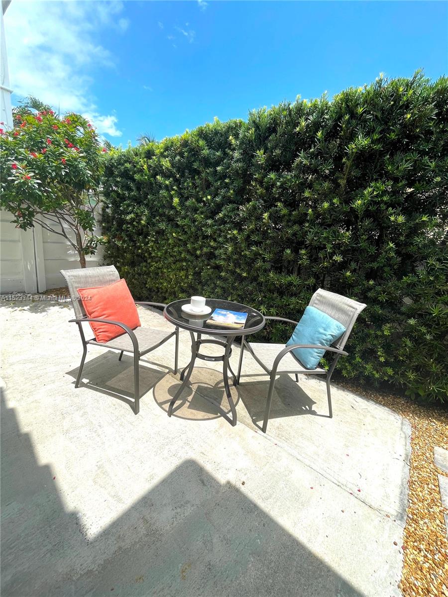 A small patio features two chairs with colorful pillows and a glass-topped bistro table — 331 Desoto St, Hollywood FL 33019, HOLLYWOOD, FL