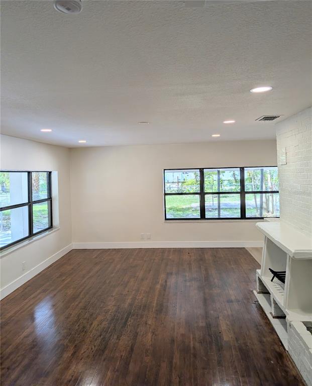 A living room features dark wood flooring, white walls, recessed lighting, and a white fireplace — 8206 N 19TH STREET, TAMPA, FL
