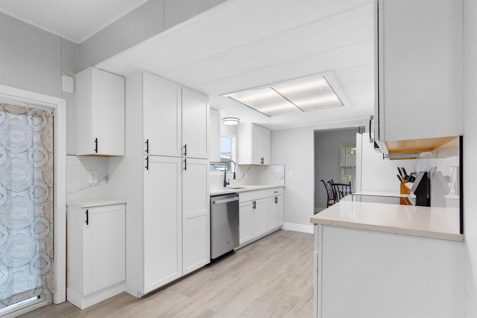 A bright kitchen features white cabinets, stainless steel appliances, and light-colored wood-look flooring — 3008 Bimini Bay, Boynton Beach FL 33436, BOYNTON BEACH, FL