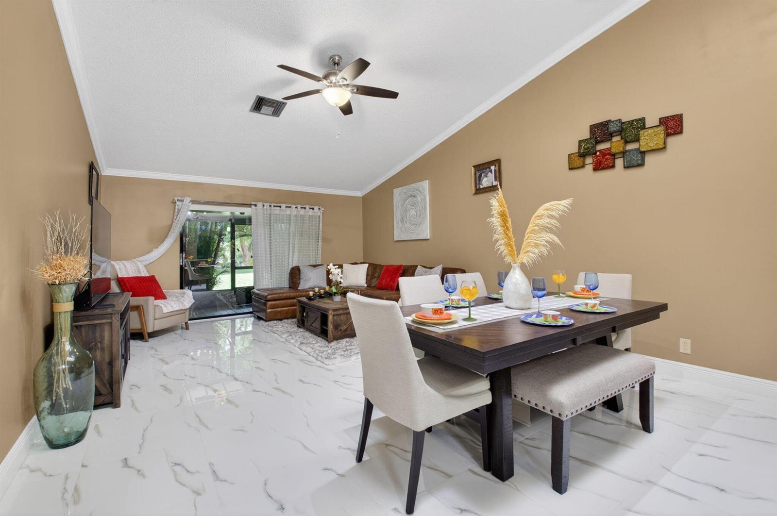 A dining area and living room with marble-look tile floors, tan walls, and vaulted ceilings — 22602 Vistawood Way, Boca Raton FL 33428, BOCA RATON, FL