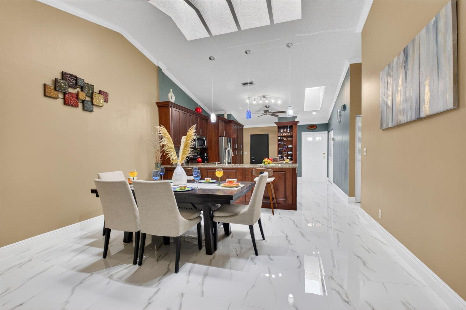 A dining area with a dark wood table and chairs sits before an open kitchen — 22602 Vistawood Way, Boca Raton FL 33428, BOCA RATON, FL