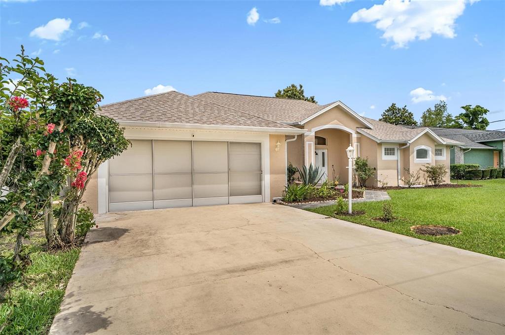 A single-story house with a beige stucco exterior, a two-car garage, and a concrete driveway — 3 WALLA PLACE, PALM COAST, FL