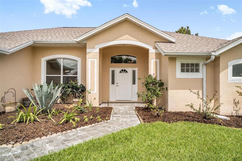 The exterior of a beige house features a white front door and a stone walkway — 3 WALLA PLACE, PALM COAST, FL