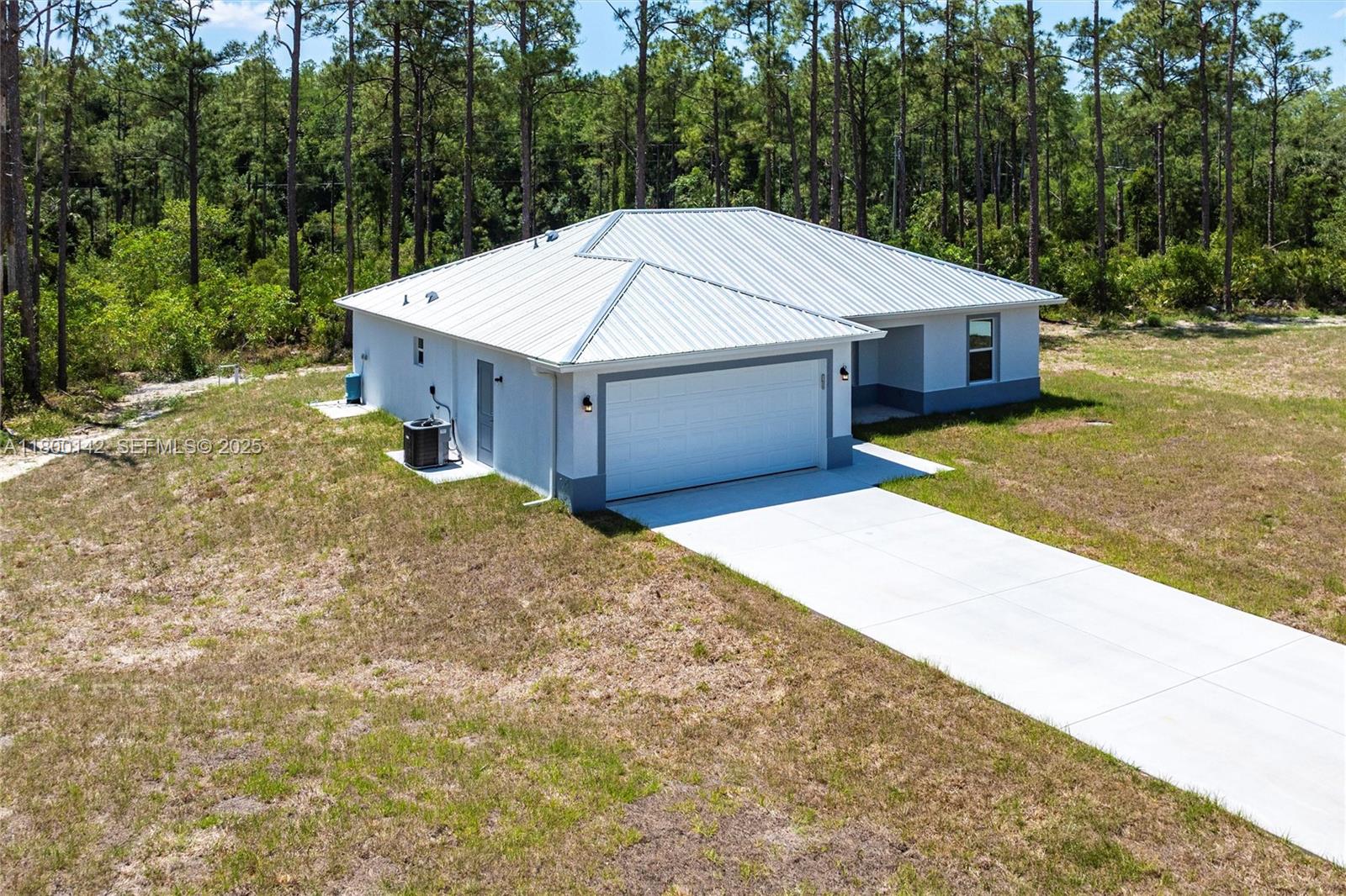 An aerial view shows a single-story house with a white metal roof and concrete driveway — 2004 Rosa Ct, Lehigh Acres FL 33972, LEHIGH ACRES, FL