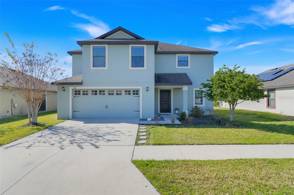 A two-story, light blue suburban house with a two-car garage and a front lawn — 5660 ELSINORE WAY, LAKELAND, FL