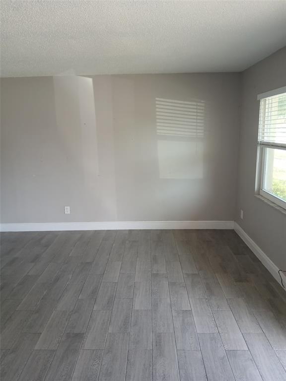 An empty room features gray wood-look tile flooring, light gray walls, and a single window — 38939 NORTH AVENUE UNIT 2, ZEPHYRHILLS, FL