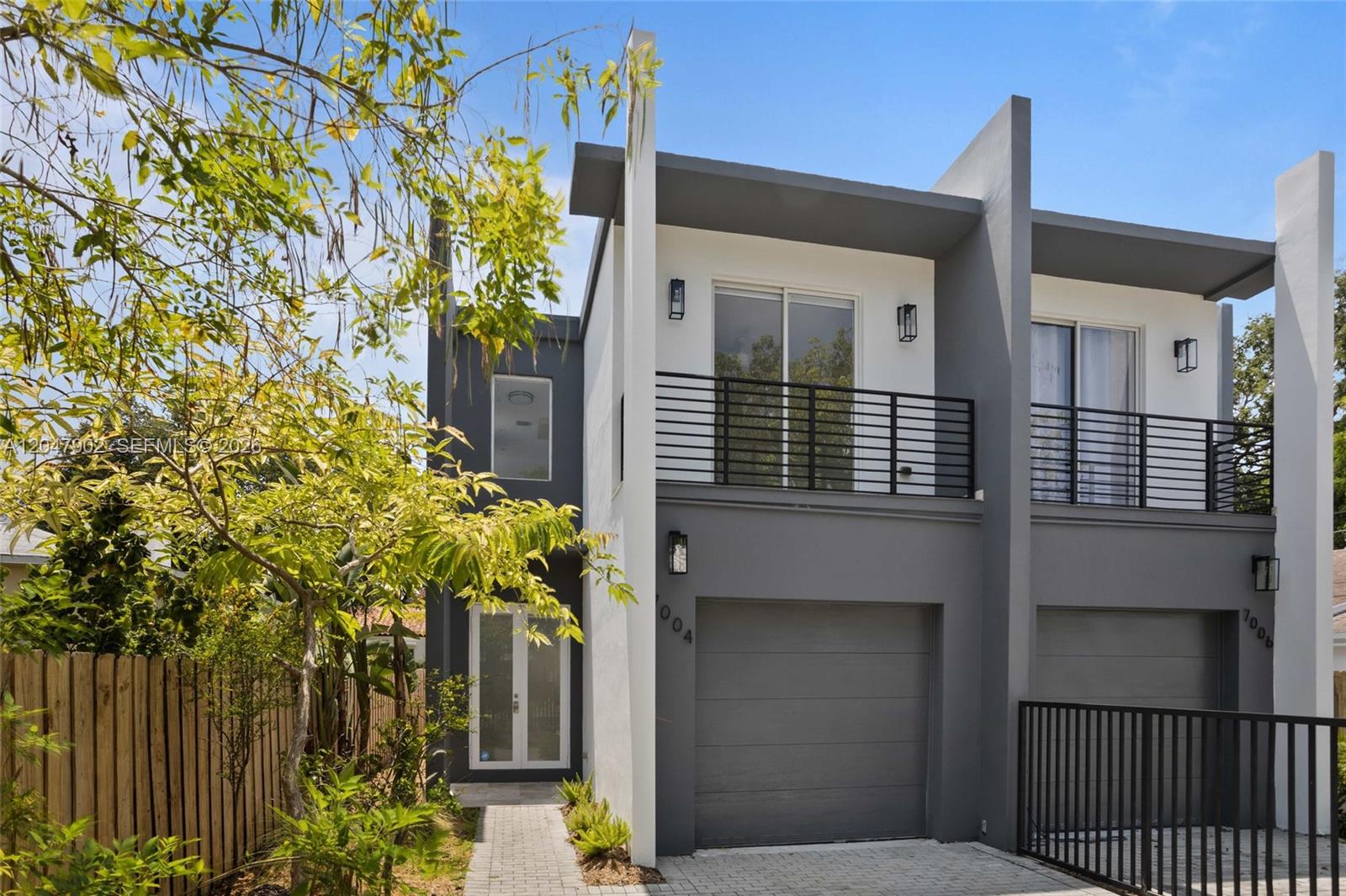 A modern two-story duplex with gray and white exterior walls, balconies, and attached garages — 7004 NE 5th Ave, Miami FL 33138, MIAMI, FL