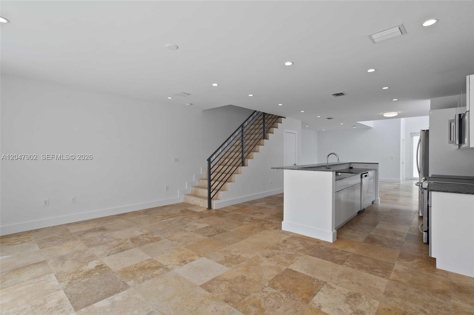 An open-concept kitchen and living area features tile flooring, a staircase, and a kitchen island — 7004 NE 5th Ave, Miami FL 33138, MIAMI, FL