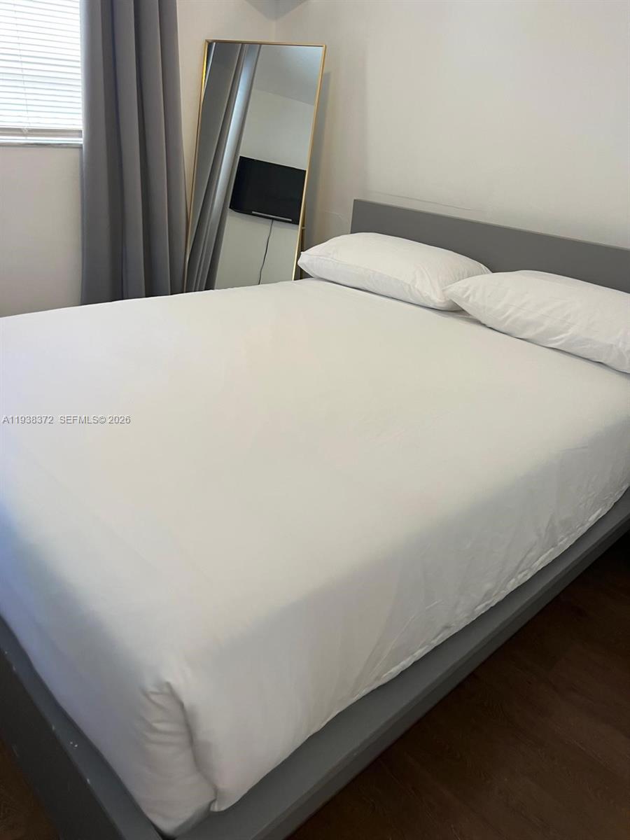 A bedroom features a gray bed frame, white bedding, and a full-length gold-framed mirror — 740 Michigan Ave # 5, Miami Beach FL 33139, MIAMI BEACH, FL