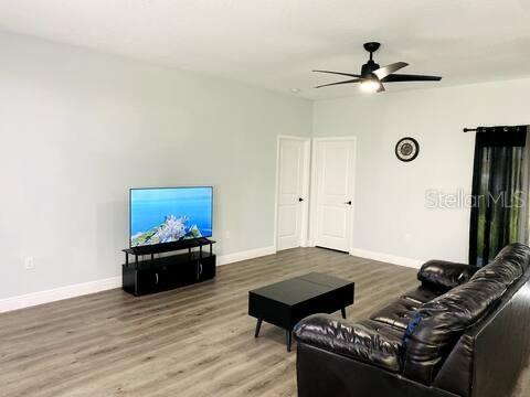 A living room features light blue walls, wood-look flooring, a black TV stand, and a sofa — 14358 MCFARLAND AVENUE, PORT CHARLOTTE, FL