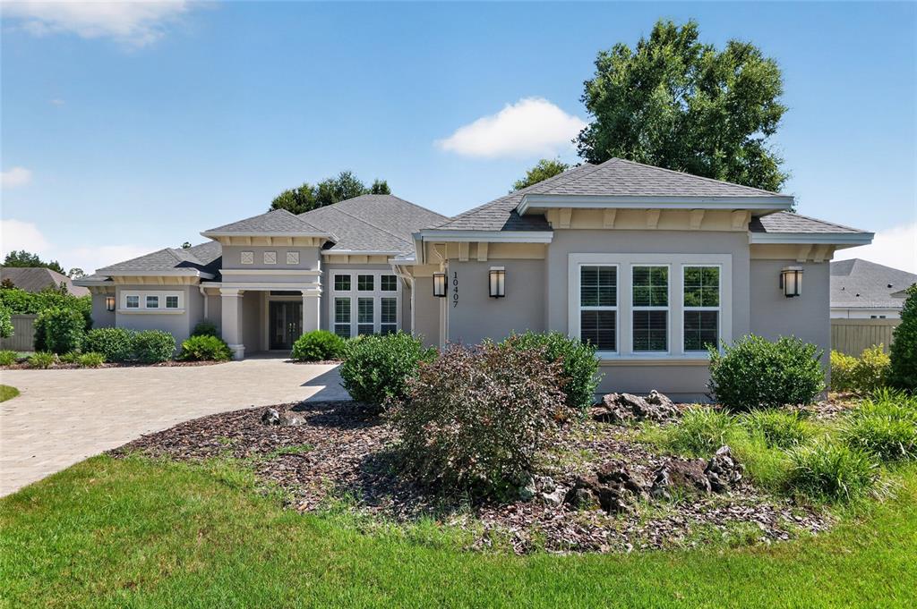 A single-story house with a gray stucco exterior, a paved driveway, and landscaped front yard — 10407 SW 26TH PLACE, GAINESVILLE, FL