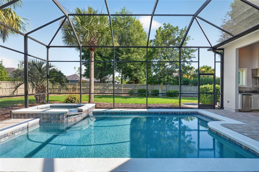 A screened-in pool and spa area with a paved deck and a fenced backyard — 10407 SW 26TH PLACE, GAINESVILLE, FL