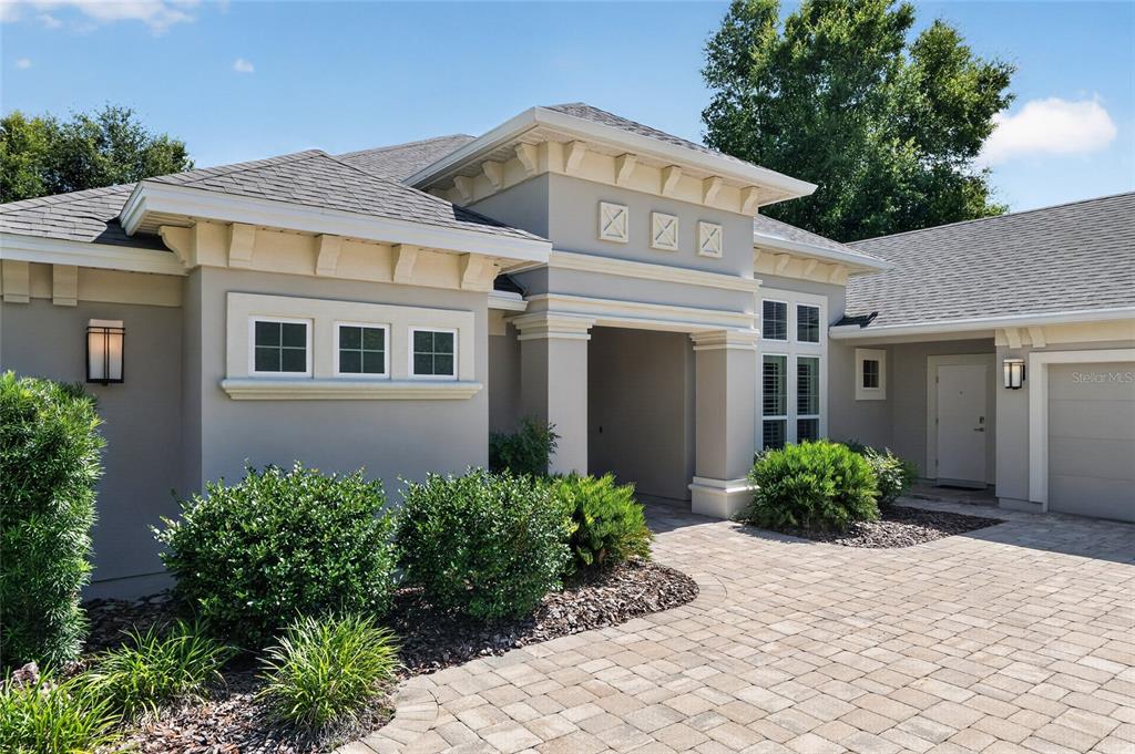 The exterior of a modern house features a paved driveway, stucco walls, and landscaping — 10407 SW 26TH PLACE, GAINESVILLE, FL