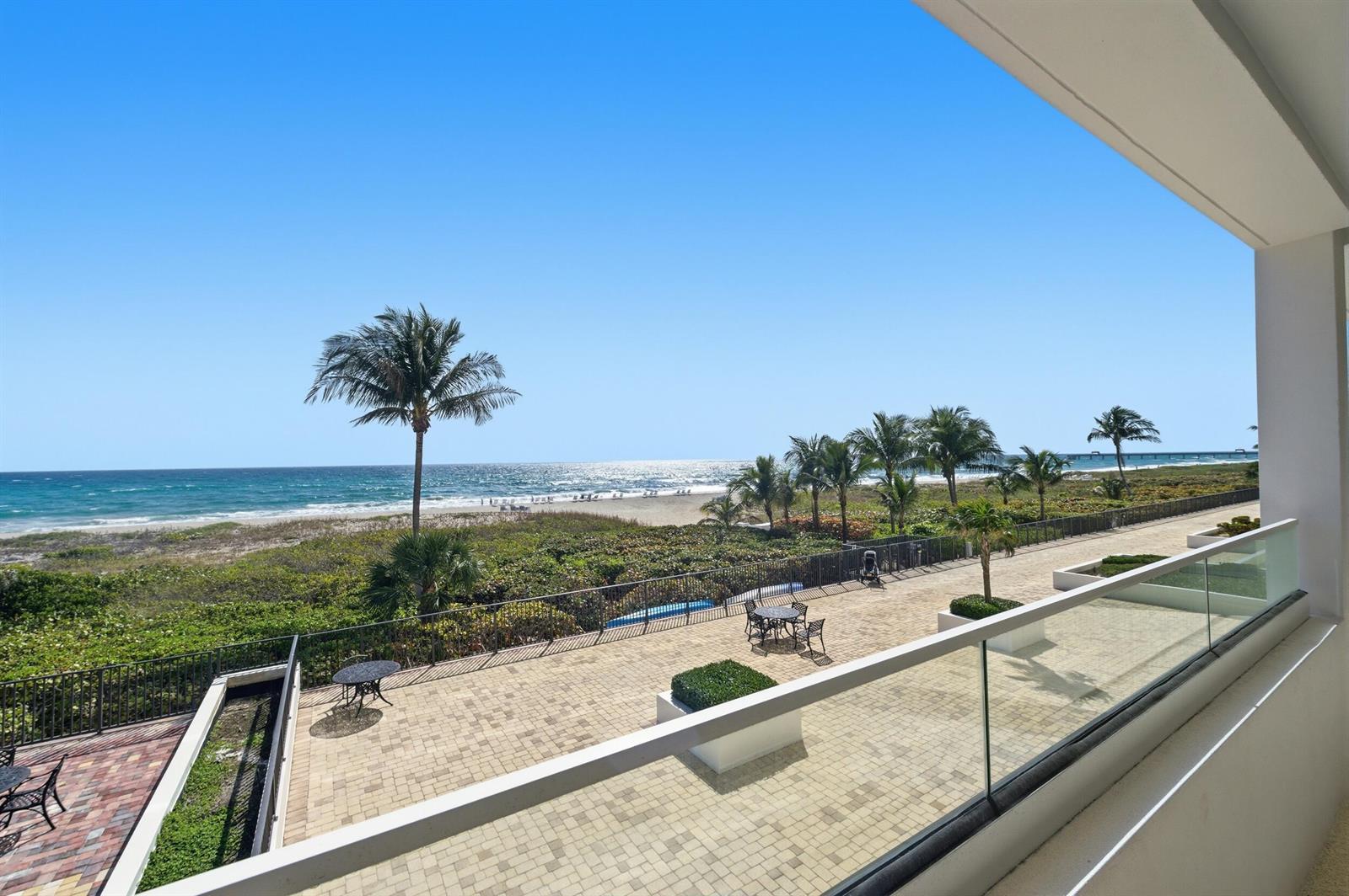 A balcony overlooks a paved patio, lush landscaping, a sandy beach, and the ocean — 2800 S Ocean Boulevard # 2a, Boca Raton FL 33432, BOCA RATON, FL