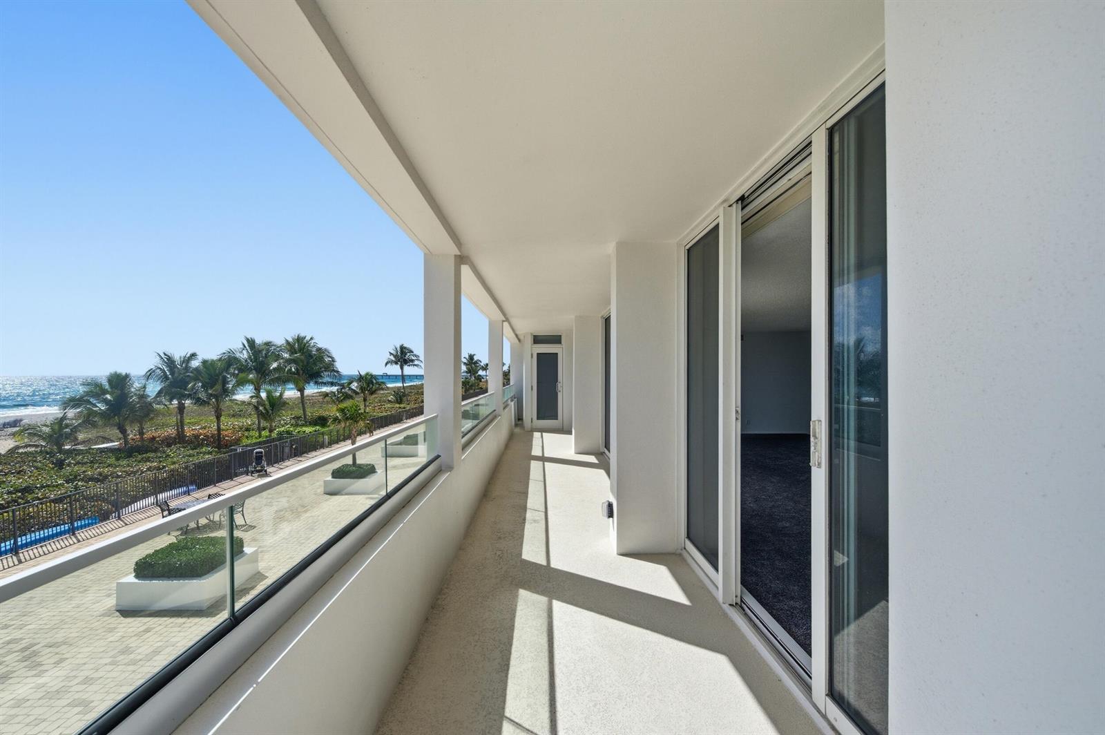 A long, covered balcony with glass railings overlooks a beach, palm trees, and the ocean — 2800 S Ocean Boulevard # 2a, Boca Raton FL 33432, BOCA RATON, FL