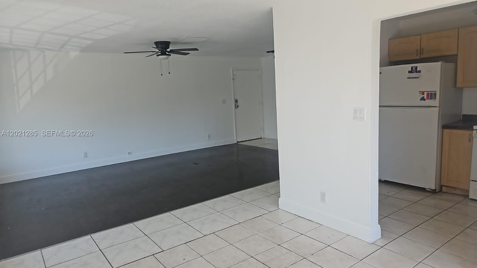 A living area with dark flooring transitions into a tiled kitchen with light wood cabinets — 5300 NW 18th Ct # 4I, Lauderhill FL 33313, LAUDERHILL, FL