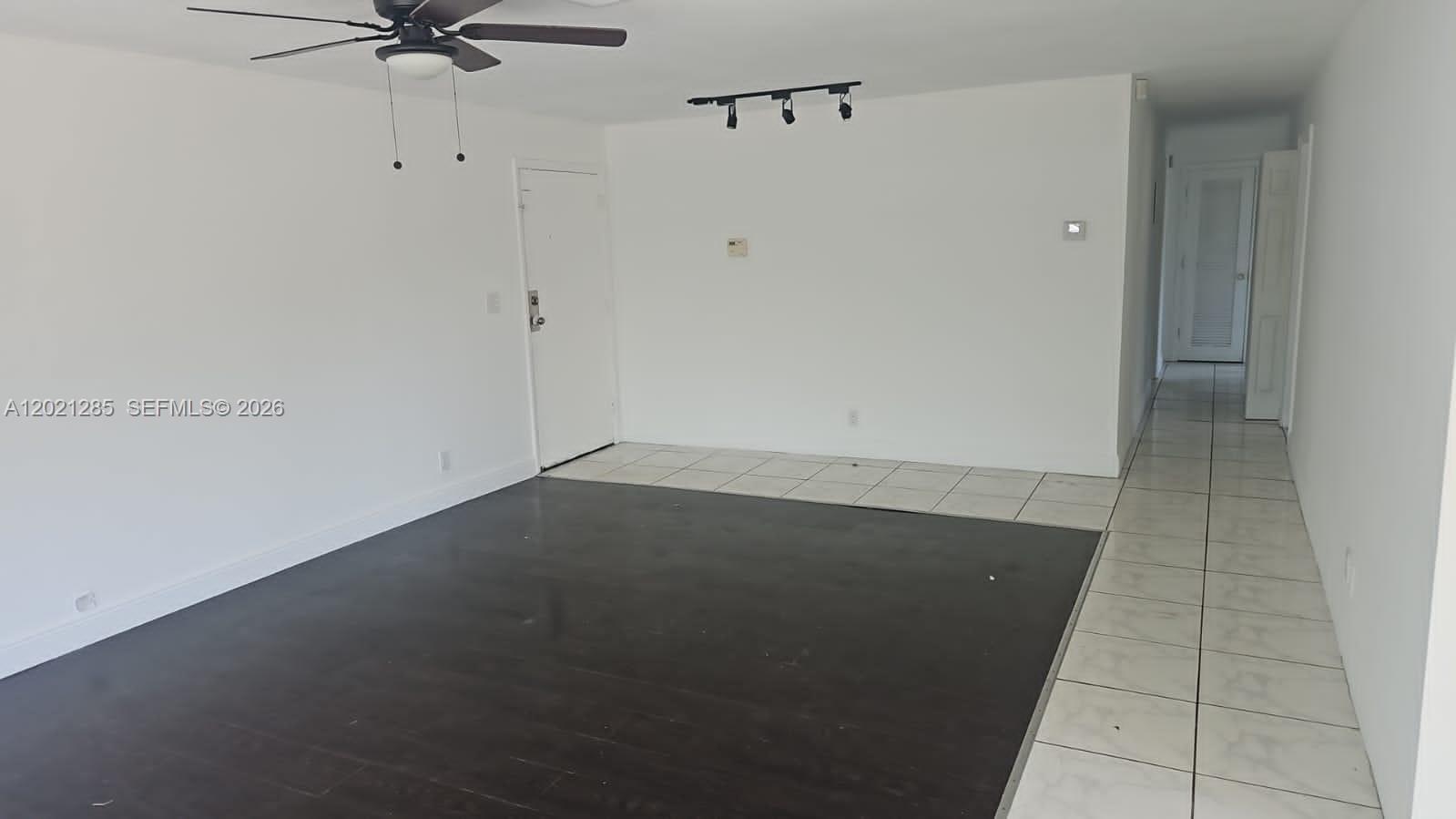 An empty room features dark wood flooring, white tile borders, a ceiling fan, and track lighting — 5300 NW 18th Ct # 4I, Lauderhill FL 33313, LAUDERHILL, FL