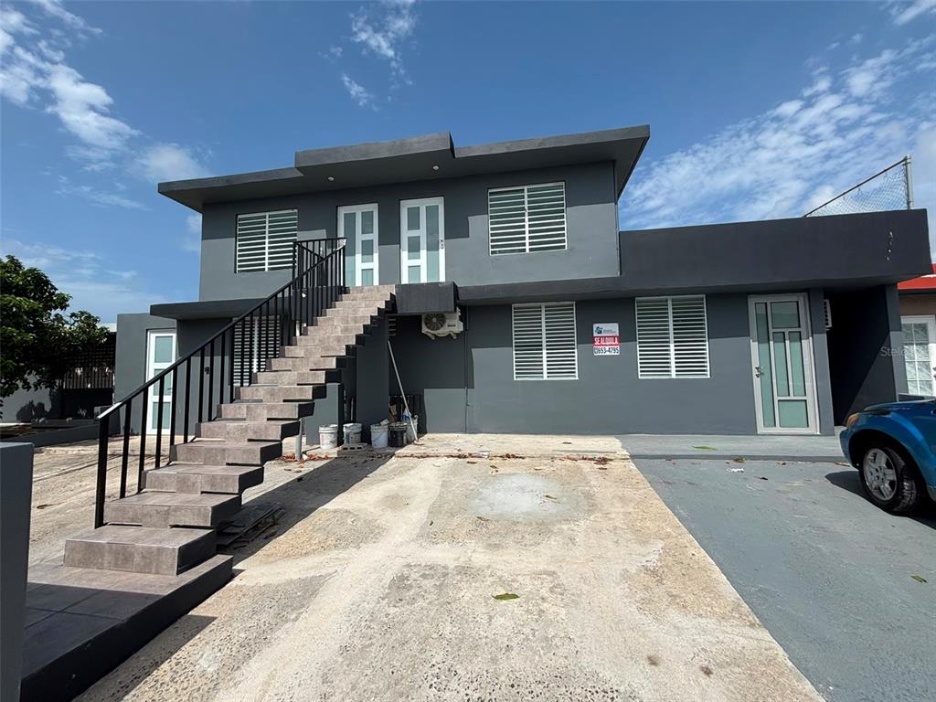A two-story gray house features an exterior staircase leading to an upper-level entrance — 18-6 18 Street SABANA GARDENS, CAROLINA, PR