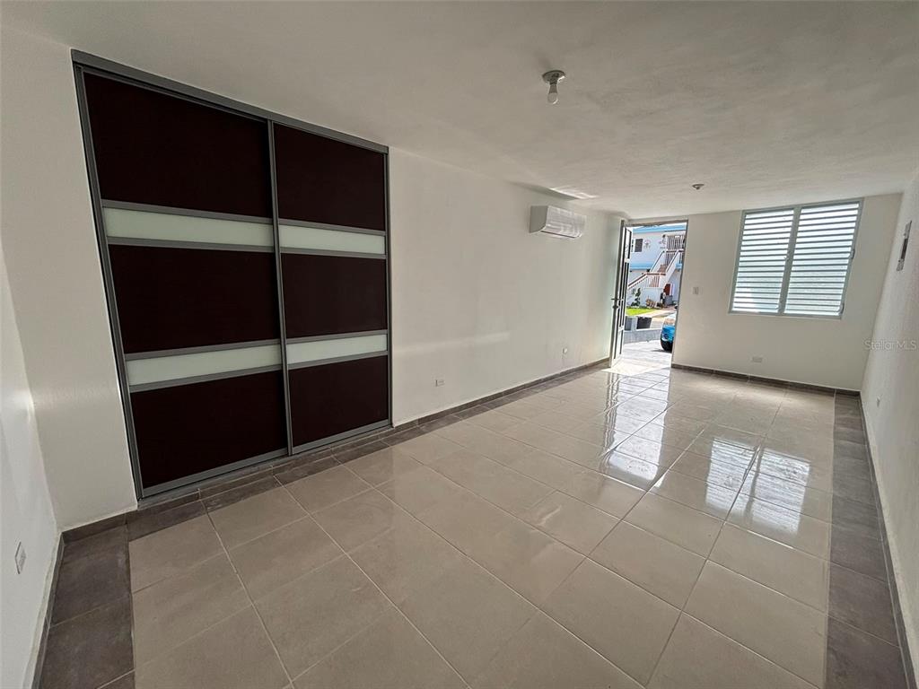 A room with light tile floors, a dark sliding closet, and an open exterior door — 18-6 18 Street SABANA GARDENS, CAROLINA, PR