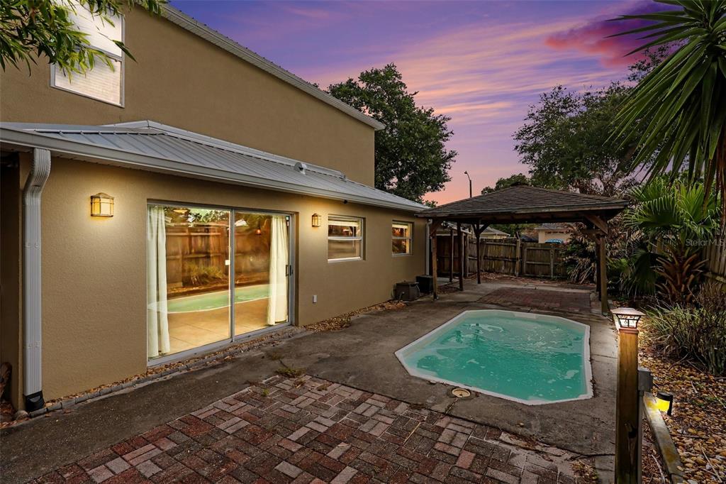A backyard features a small pool, a wooden gazebo, and a tan house exterior — 2415 SAINT PAULS DRIVE, TITUSVILLE, FL