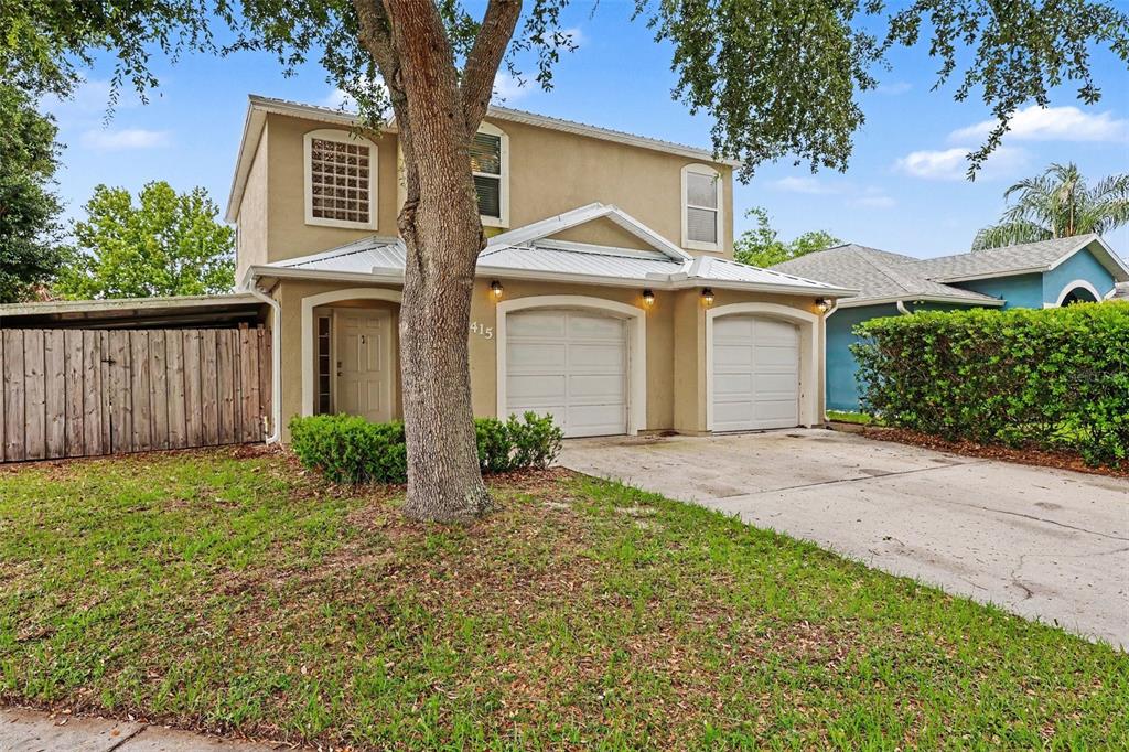 A two-story duplex with a tan stucco exterior, two garage doors, and a front lawn — 2415 SAINT PAULS DRIVE, TITUSVILLE, FL