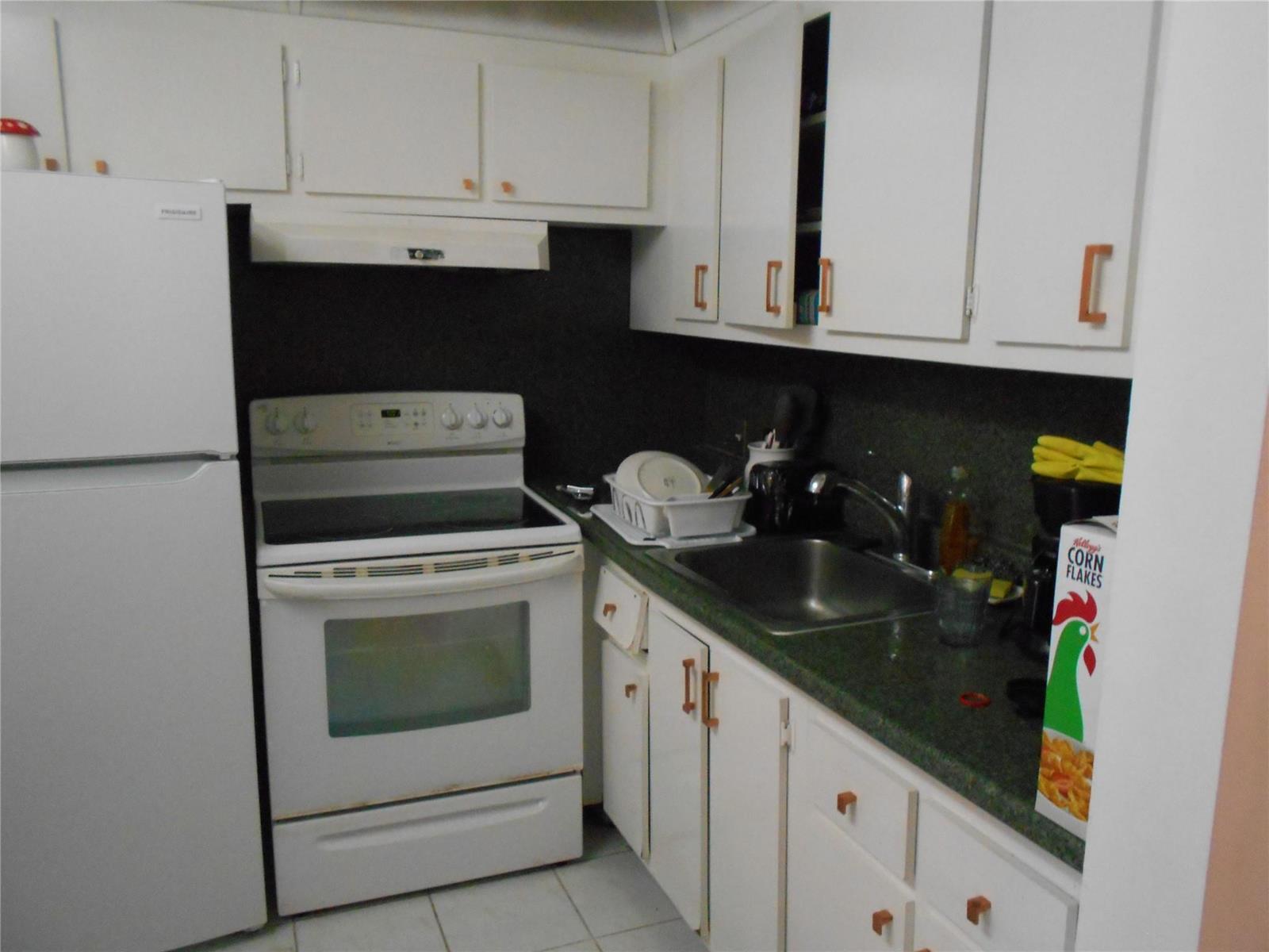A kitchen features white cabinets, a white stove, a refrigerator, and a dark countertop — 91 Preston C # 91, Boca Raton FL 33434, BOCA RATON, FL