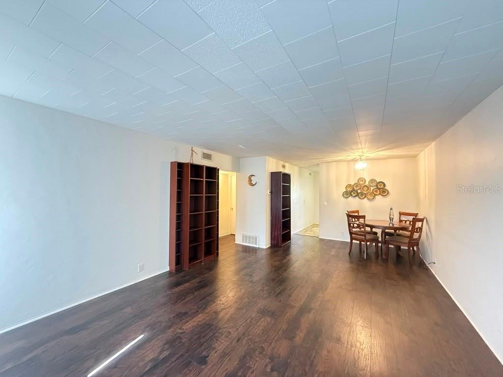 A dining area and living space feature dark wood flooring and a white tiled ceiling — 4032 57TH STREET N UNIT 264, KENNETH CITY, FL