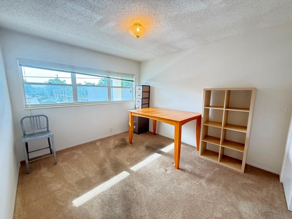 A room with beige carpet, a wooden desk, a shelving unit, and a large window — 4032 57TH STREET N UNIT 264, KENNETH CITY, FL