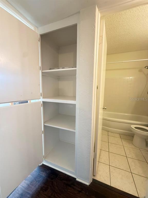 An open white linen closet stands next to a bathroom with a toilet and tub — 4032 57TH STREET N UNIT 264, KENNETH CITY, FL