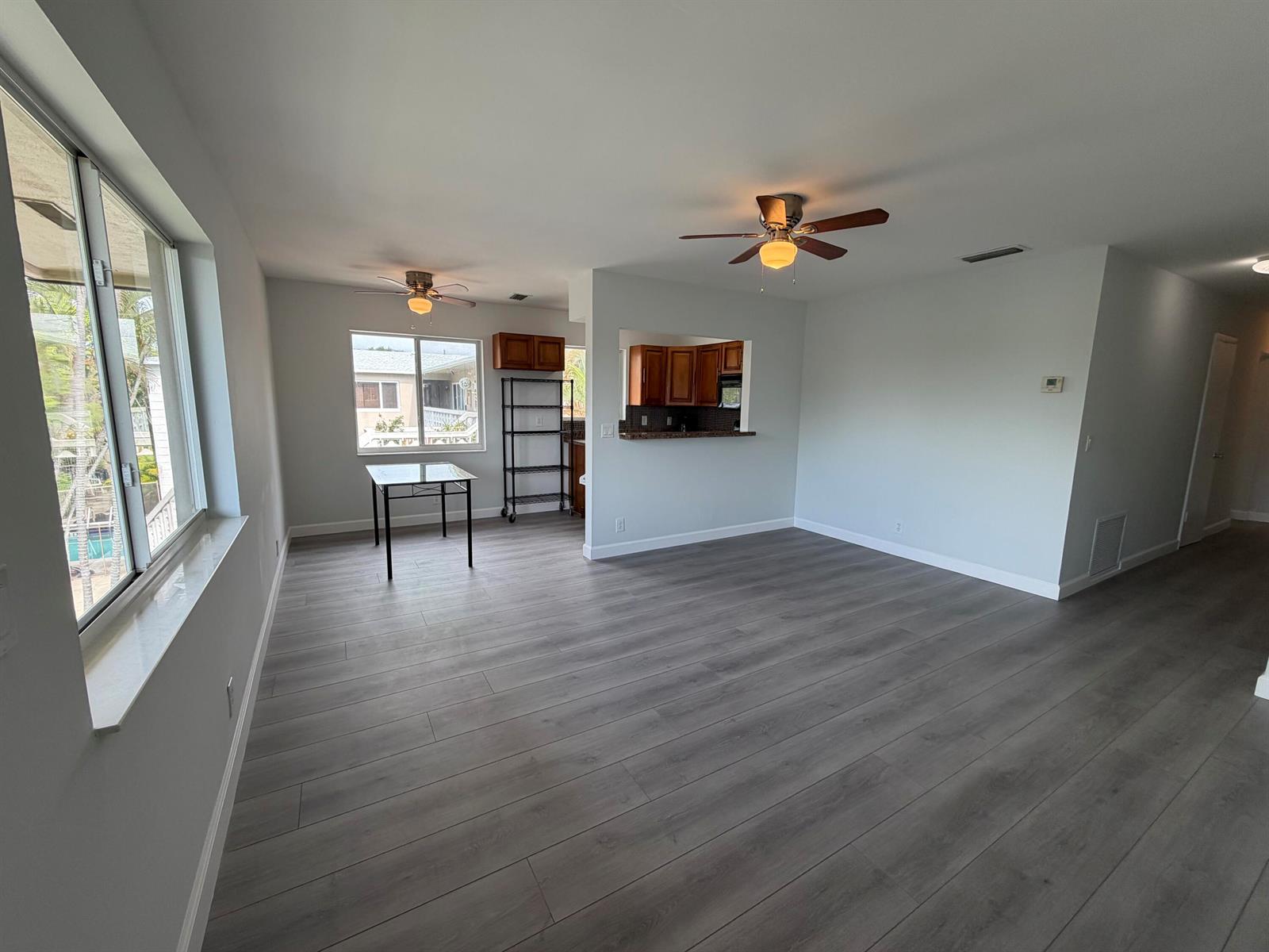 A kitchen features wood cabinets, granite countertops, a black appliance suite, and light wood flooring — 510 SW 15th Street # 204, Pompano Beach FL 33060, POMPANO BEACH, FL