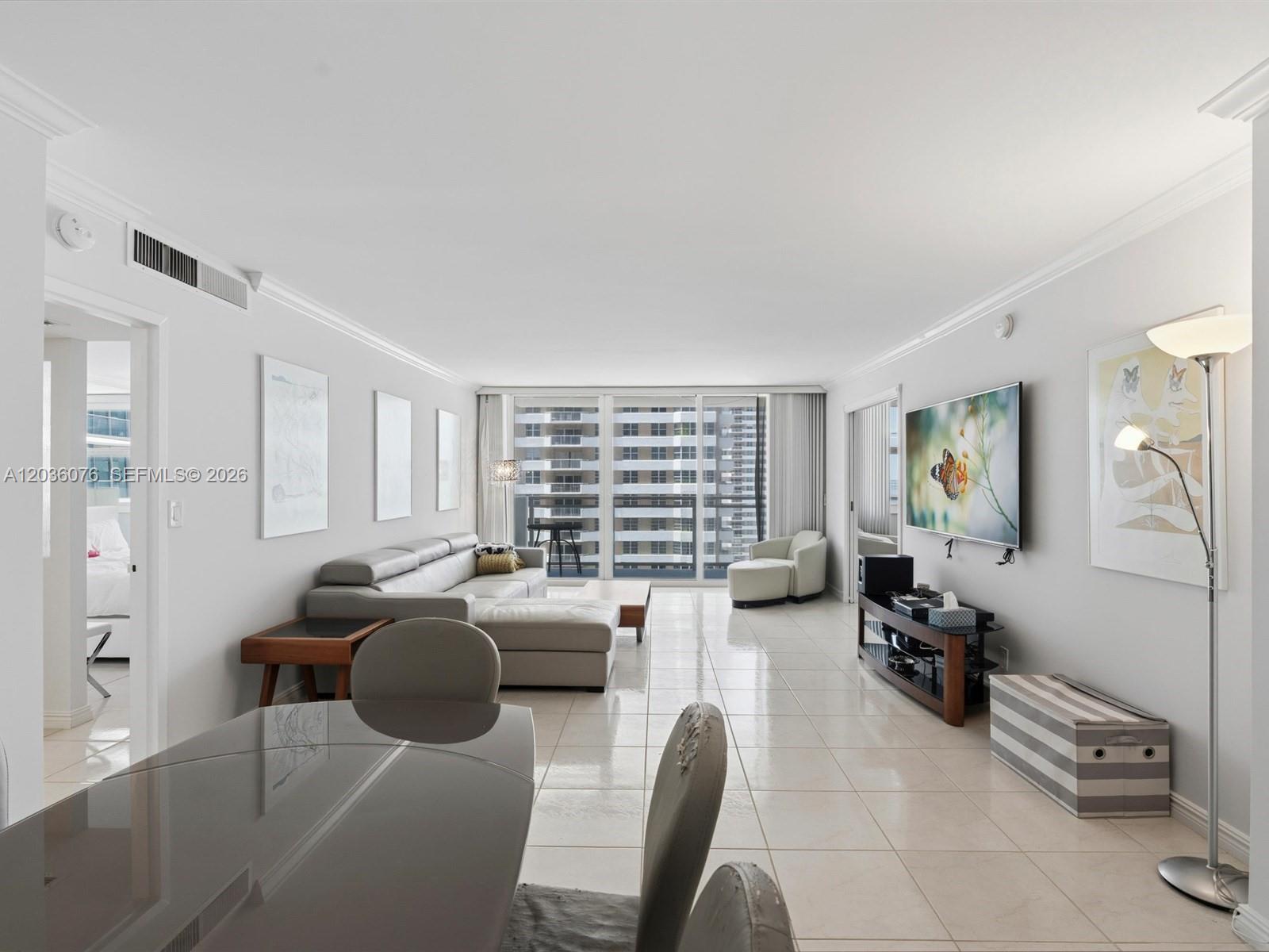 A living room features a grey sectional sofa, a wall-mounted television, and tile flooring — 2030 S Ocean Dr # 1123, Hallandale Beach FL 33009, HALLANDALE BEACH, FL