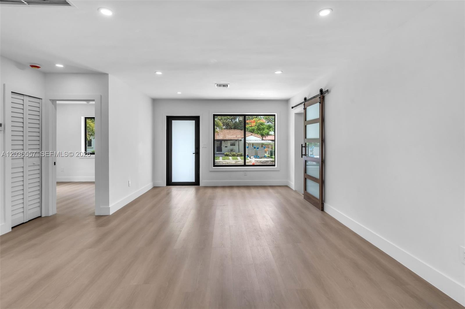 A bright room features light wood flooring, recessed lighting, a sliding barn door, and windows — 4353 SW 2nd St, Miami FL 33134, MIAMI, FL