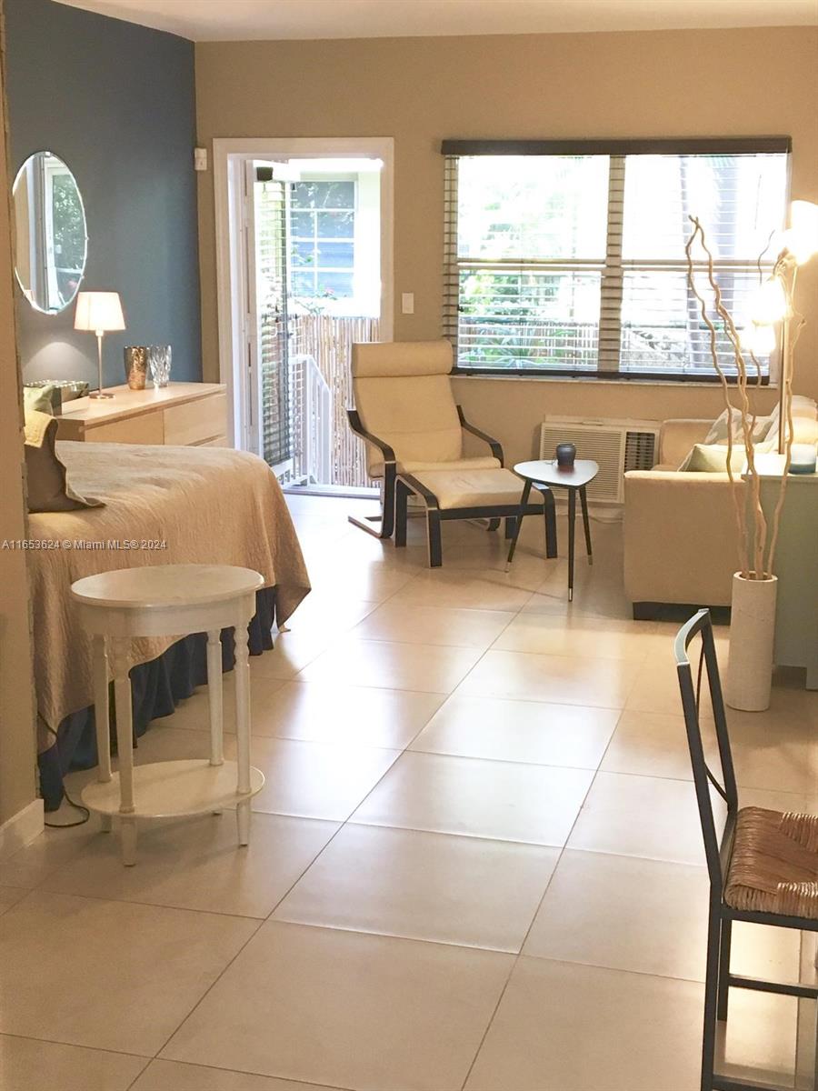 A bedroom with tile floors, a bed, an armchair, and a door leading to a balcony — 1228 Pennsylvania Ave # 2, Miami Beach FL 33139, MIAMI BEACH, FL