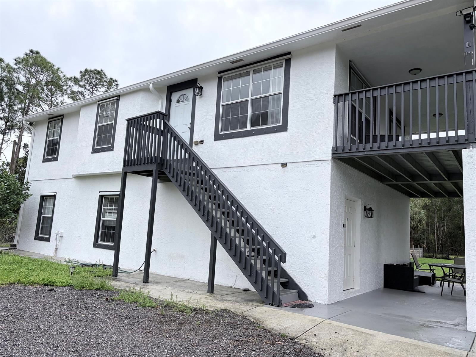 A two-story white stucco building features a dark gray exterior staircase and a covered patio — 11128 N 59th St Street N, FL 33411, FL