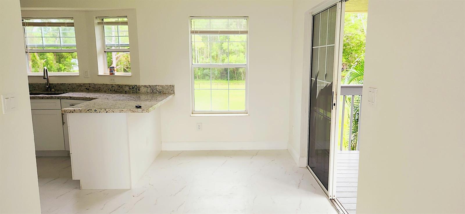 A kitchen with granite countertops and white cabinets opens to a dining area with tile — 11128 N 59th St Street N, FL 33411, FL