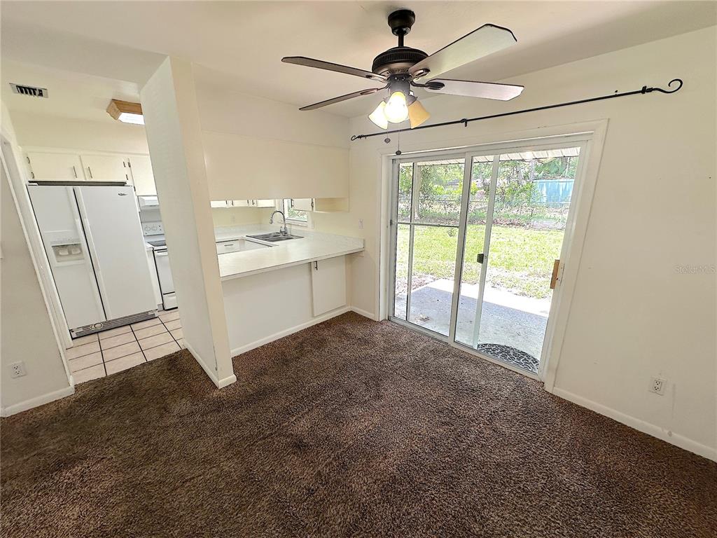 A dining area with brown carpet features a ceiling fan and sliding glass doors — 4146 NW 30TH TERRACE, GAINESVILLE, FL