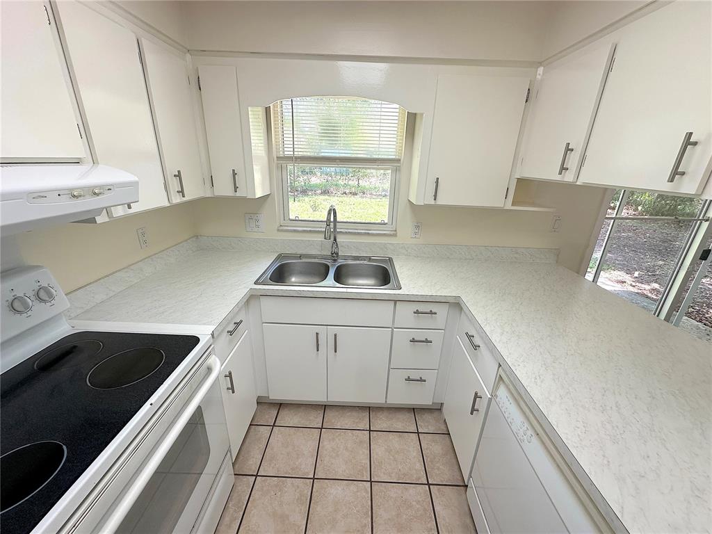 A kitchen features white cabinets, laminate countertops, a double sink, and a tiled floor — 4146 NW 30TH TERRACE, GAINESVILLE, FL